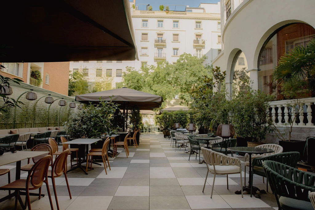 Mesas de la terraza de FOX entre plantas, bajo la luz del jardín