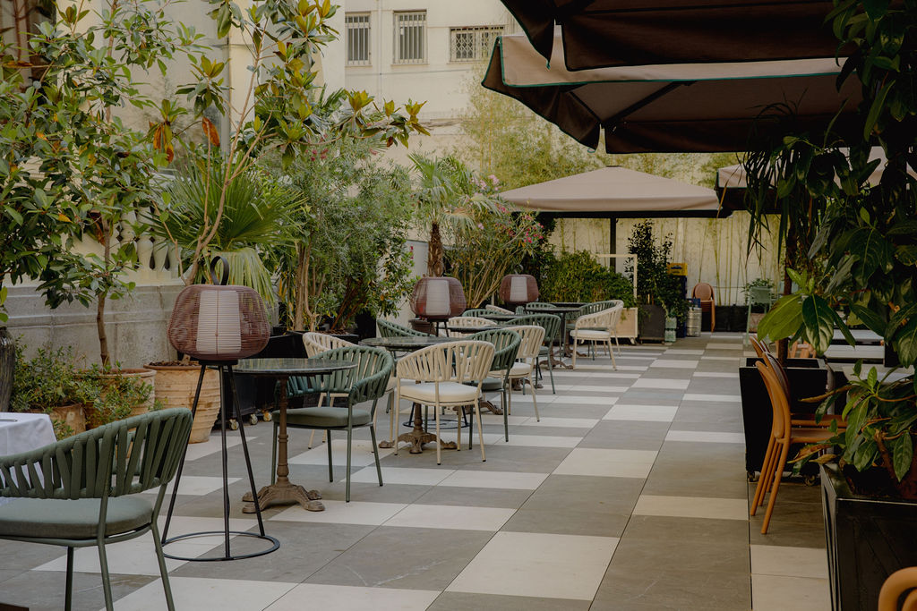 La terraza ajardinada de FOX, con butacas verdes y mesas entre plantas